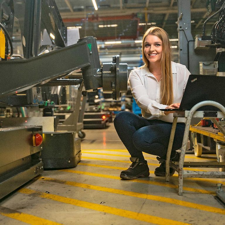 jobs-teaser-jobboard-image Mujer está sentada con su ordenador en una nave de producción