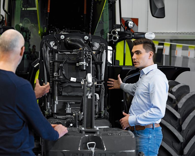 working-areas-stage-pic Colegas delante de un tractor con el capó abierto