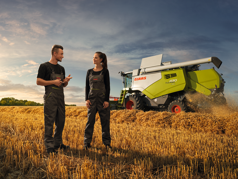 Apprenticeship Zwei Personen auf dem Feld vor einem Mähdrescher.