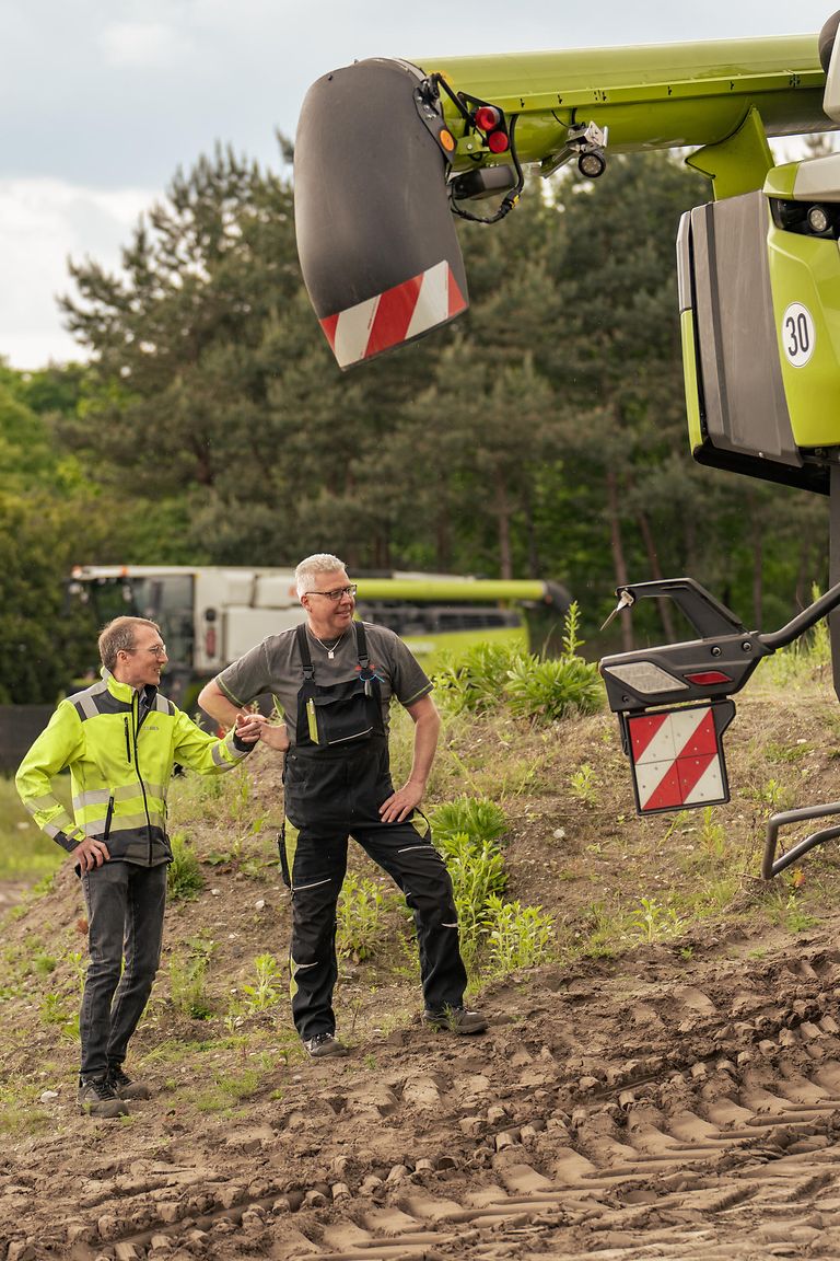 professionals-stage-pic Kollegen stehen vor Mähdrescher auf Testgelände