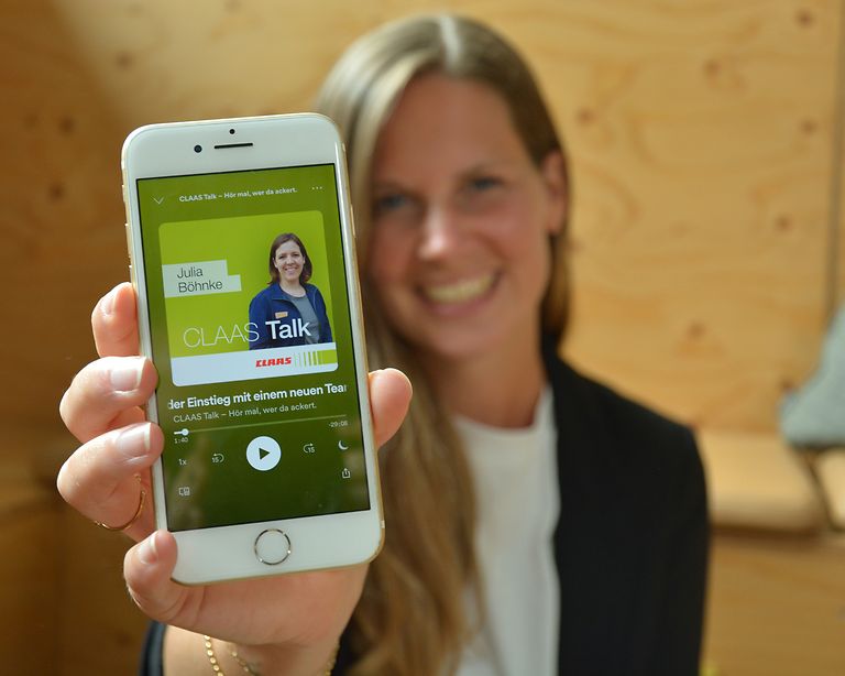 Podcasthörerin zeigt Podcast-Folge auf Handy