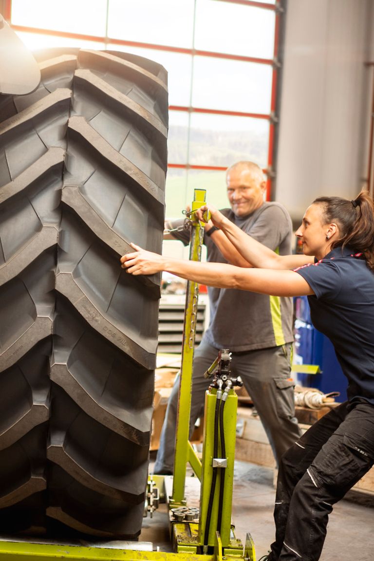service-technician-stage-pic Landmaschinenmechatronikerin und Kollege wechseln Reifen