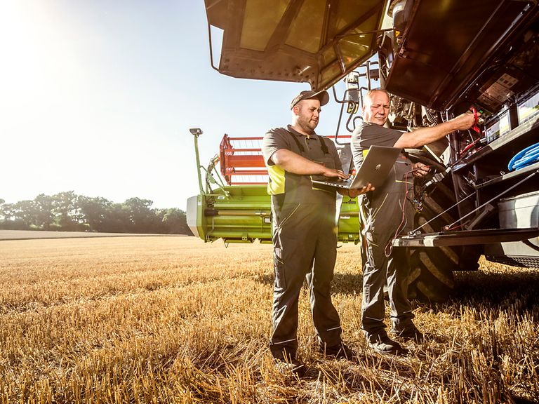 471247_27 2 Landmaschinentechniker stehen neben Mähdresche auf Feld