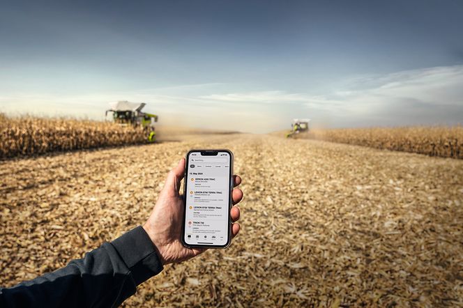 high-tech-meets-purpose-infrastructure (1) Hand mit Handy, Maschinen auf Feld im Hintergrund